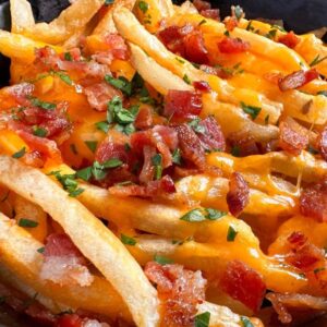 Delicious cheese fries topped with bacon and parsley plate of gooey