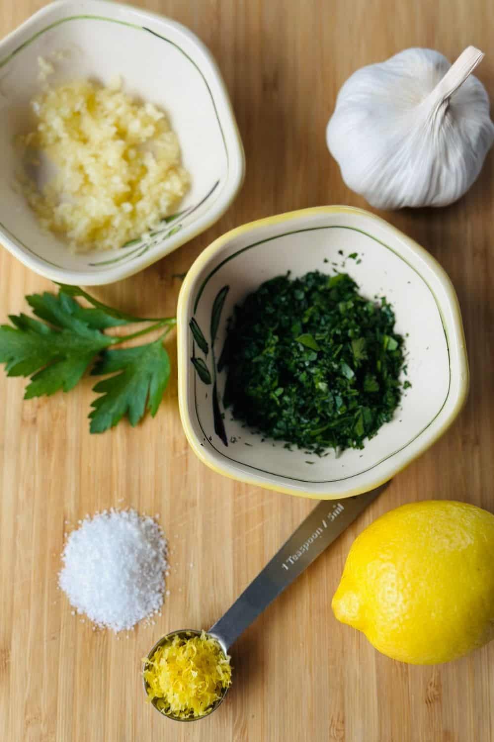 Wooden cutting board containing all the ingredients required for this garlic herb butter recipe.